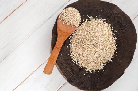 Burlap sack with pearl barley spilling out over a white backgroundの写真素材