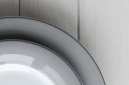 White round classical porcelain plates with a gray pattern stand on a white wooden table