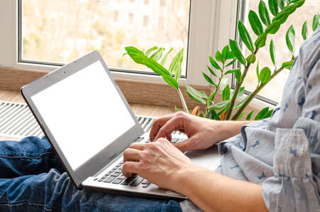 Concept of distance learning, isolation, business, shopping online. Remote working from home. Freelancer workplace in kitchen with laptop. Close up of man hands.の写真素材