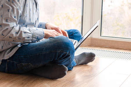 Concept of distance learning, isolation, business, shopping online. Remote working from home. Freelancer workplace in kitchen with laptop. Close up of man hands.の写真素材