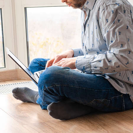 Concept of distance learning, isolation, business, shopping online. Remote working from home. Freelancer workplace in kitchen with laptop. Close up of man hands.の写真素材