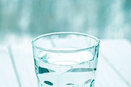 A glass with pure clear melt water stands on a white table