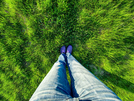Womens feet in blue jeans against bright green grassの写真素材
