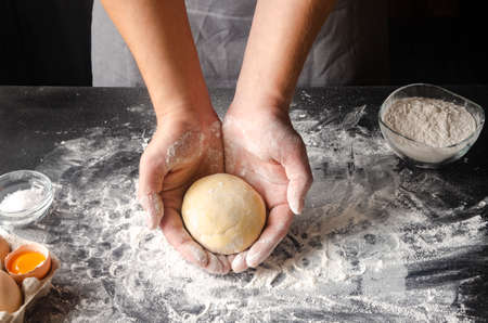 The mans hands knead the dough for the preparation of cherry strudelの写真素材