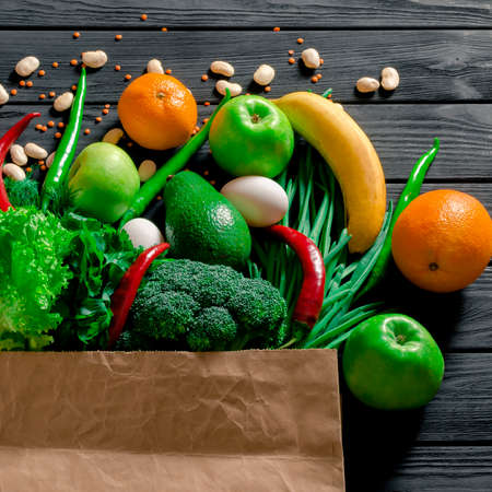 Paper bag of different tropical fresh fruits and vegetables. Healthy eating and grocery shopping concept. Top viewの写真素材
