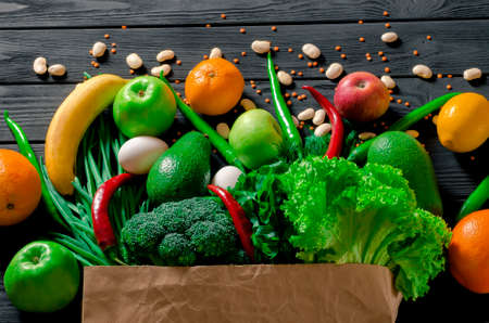 Paper bag of different tropical fresh fruits and vegetables. Healthy eating and grocery shopping concept. Top viewの写真素材