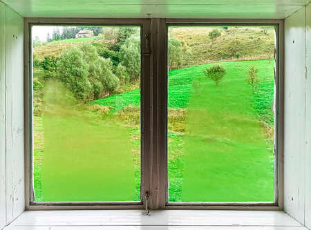 A window. view through a window to a wonderful green mountain landscape on vacationの写真素材