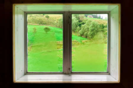 Blurred. A window. view through a window to a wonderful green mountain landscape on vacationの写真素材