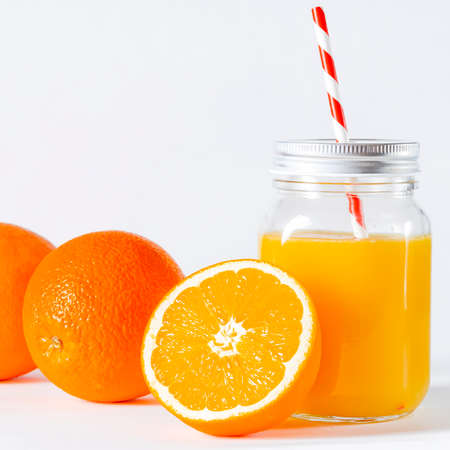 Orange juice in fast food closed cup with tube and slice of orange isolated on white. Glass jar with a tube with freshly squeezed orange juiceの写真素材