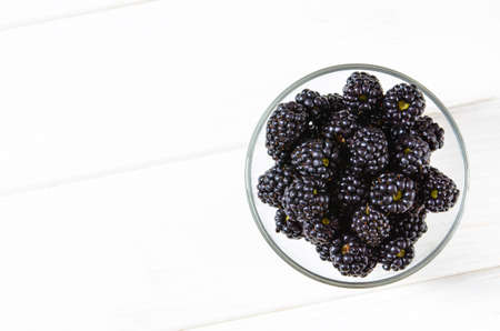 Fresh ripe blackberries in bowls on white wooden table, flat layの写真素材