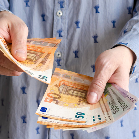 Businessman's hands exchanging euro on white background, closeup shot. Male counts salary in euro banknotes. Saving money, withdrawal banking deposit. European money. Financial crisisの写真素材