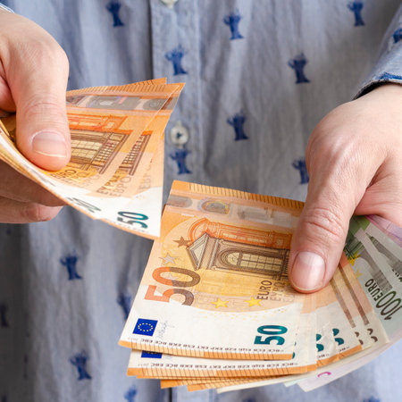 Businessman's hands exchanging euro on white background, closeup shot. Male counts salary in euro banknotes. Saving money, withdrawal banking deposit. European money. Financial crisisの写真素材