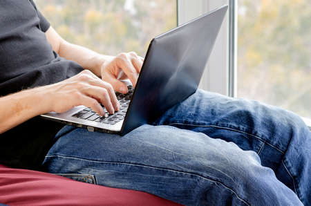 Remote working from home. Freelancer workplace in kitchen with laptop. Concept of distance learning, isolation, business, shopping online. Close up of man handsの写真素材