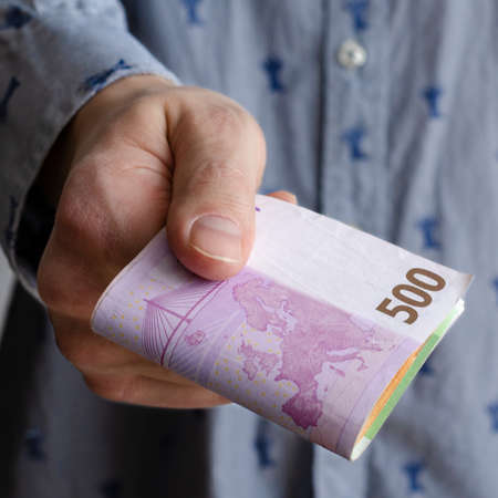 Businessman's hands exchanging euro on blue background, closeup shot. European money. Financial crisisの写真素材