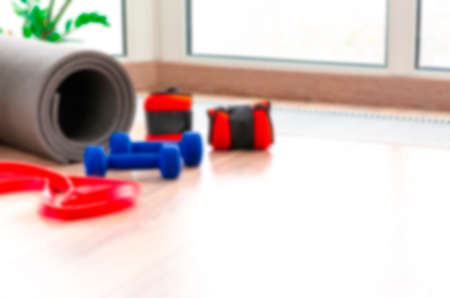 Blurred. Sports concept. Fitness kit at home. Fitness mat, weights for arms and legs, dumbbells and harness lie on the floorの写真素材