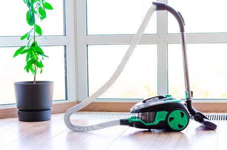 construction cleaning service. Light green vacuum cleaner on a window backgroundの写真素材
