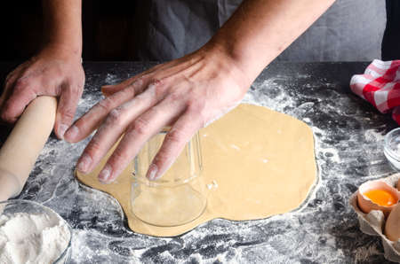 Man kneading dough on board sprinkled with flour. Ingredients for the doughの写真素材