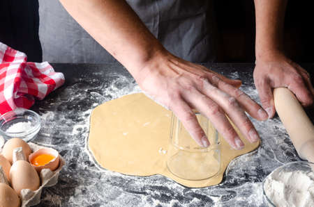Man kneading dough on board sprinkled with flour. Ingredients for the doughの写真素材