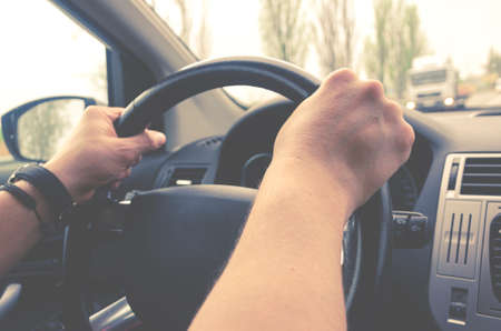 Driving a car. Men's hands hold the steering wheel while travelingの写真素材
