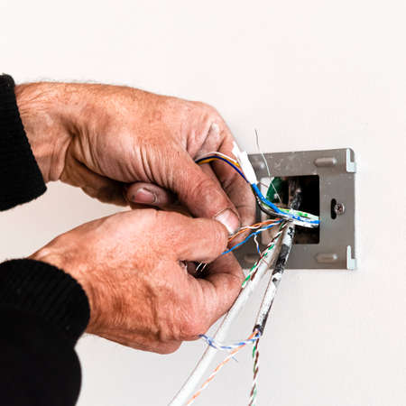 The hands of an elderly man mount a rosette in a white wall. Repair of the apartment. Internetの写真素材