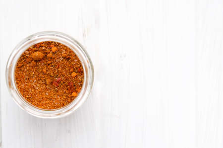 Seasoning. Bright Georgian Svan salt in a glass jar stands on a white wooden tableの写真素材