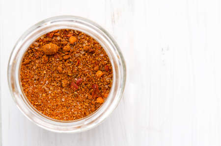 Seasoning. Bright Georgian Svan salt in a glass jar stands on a white wooden tableの写真素材