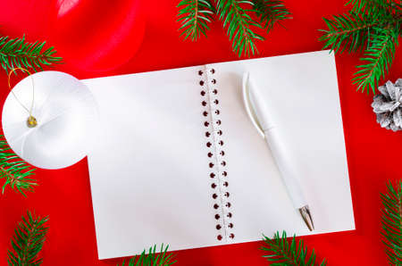 New Year background. Green fir branches with an open notebook lie on a red background.の写真素材
