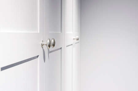 Minimal white closet or wardrobe with silver door handles. Interior object photo, Close-up and selective focus at the knob handle.の写真素材