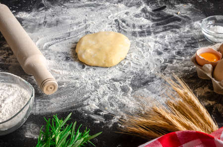 Ingredients for cooking pizzas lie on a black table. dough, eggs, earsの写真素材