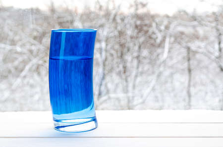 Pouring clear water into glass on nature background. A blue glassの写真素材
