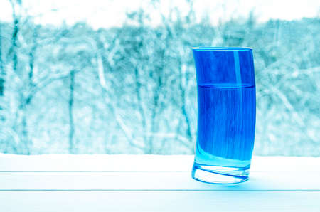Pouring clear water into glass on nature background. A blue glassの写真素材