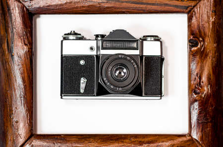 An old camera lies on a white background in a brown wooden frame. photoの写真素材