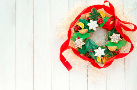 A Christmas gingerbread in the shape of a Christmas wreath lies on a white wooden background. Christmas card with space for text. Decorative composition of a Christmas wreath, gingerbread cookiesの写真素材