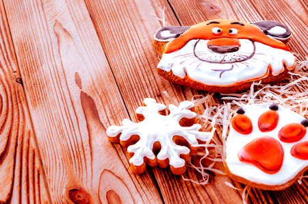 Christmas gingerbread in the shape of a tiger's head and paw lie on a wooden background. Christmas card with space for textの写真素材