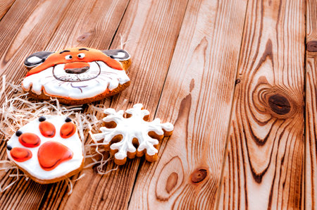 Christmas gingerbread in the shape of a tiger's head and paw lie on a wooden background. Christmas card with space for textの写真素材