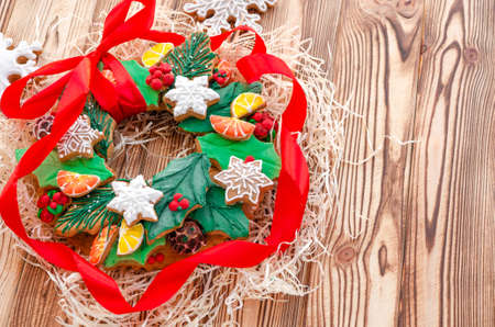 A Christmas gingerbread in the shape of a Christmas wreath lies on a wooden background. Christmas card with space for text. Decorative composition of a Christmas wreath, gingerbread cookiesの写真素材