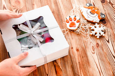 Christmas gift in the hands of a man on a wooden background. Christmas gingerbreadの写真素材