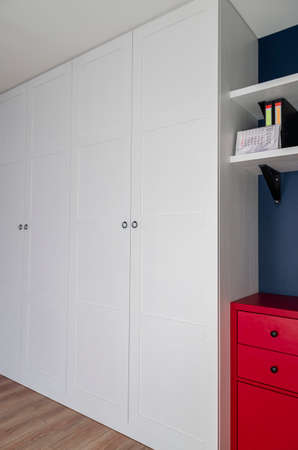 The interior of the apartment in the Scandinavian style. White wardrobe, red dresser and blue wall. Custom furnitureの写真素材
