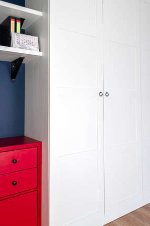 The interior of the apartment in the Scandinavian style. White wardrobe, red dresser and blue wall. Custom furnitureの写真素材