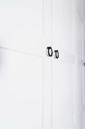 White vintage wardrobe with crown moldings wooden shelves and drawers and open facade door in light empty roomの写真素材