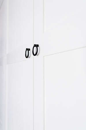 White vintage wardrobe with crown moldings wooden shelves and drawers and open facade door in light empty roomの写真素材