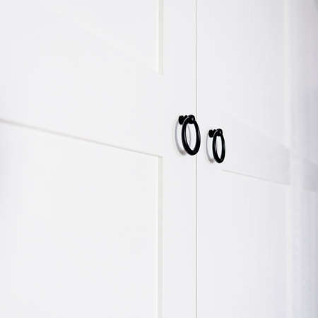 White vintage wardrobe with crown moldings wooden shelves and drawers and open facade door in light...