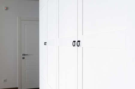 White wooden wardrobe with black handles. The interior of the apartment is in Scandinavian styleの写真素材