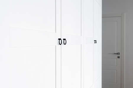 White wooden wardrobe with black handles. The interior of the apartment is in Scandinavian styleの写真素材