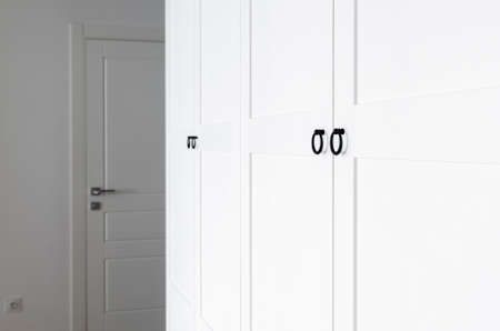 White wooden wardrobe with black handles. The interior of the apartment is in Scandinavian styleの写真素材