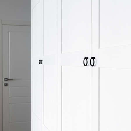 White wooden wardrobe with black handles. The interior of the apartment is in Scandinavian styleの写真素材