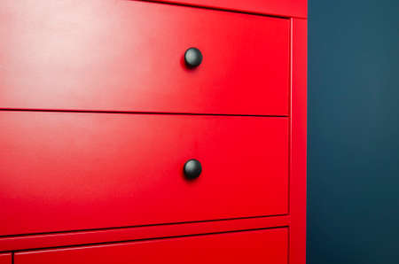Red chest of drawers in a Scandinavian interior. A red wooden cabinet with black handles stands in an apartmentの写真素材