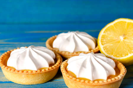 Lemon tartlets, Homemade shortbread mini tart cakes with lemon curd and whipped cream, blue background copy spaceの写真素材