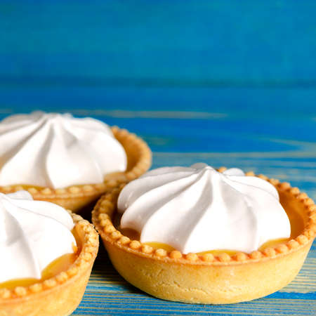 Lemon tartlets, Homemade shortbread mini tart cakes with lemon curd and whipped cream, blue background copy spaceの写真素材