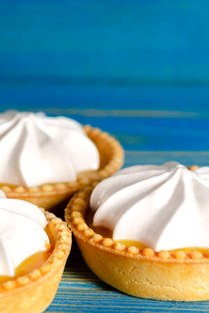 Lemon tartlets, Homemade shortbread mini tart cakes with lemon curd and whipped cream, blue background copy spaceの写真素材